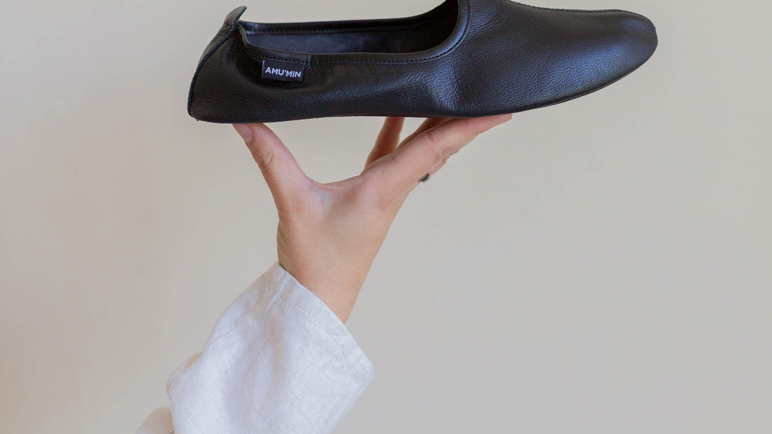 Black leather house shoe held in a hand